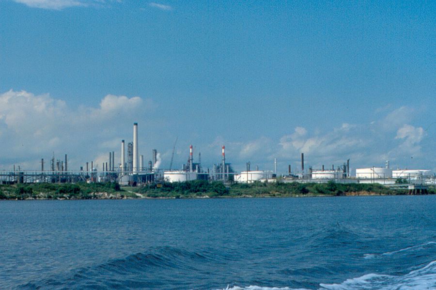 Archive: Shell Oil (now Shell–Pemex) Deer Park refinery plant and line still on the Houston Ship Channel, Texas — distillation towers, striped stacks, storage tanks, steam — 8 Jul 2010 (Roger W, CC BY-SA 2.0). Not a White House DPA signing, not a 98% utilization dashboard, not Brownsville America First Refining greenfield, and not a 2026 ceremony handshake.