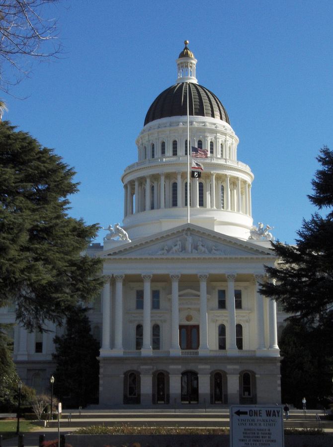 Archive: Exterior of the California State Capitol in Sacramento — dome and west facade under clear sky (Ronbo76, CC BY-SA 3.0). Not the 21 September 2026 bill-signing ceremony, not Newsom at the lectern day-of, not a chaptered-bill stamp photograph, and not a data-center construction site.