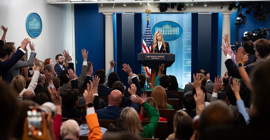 Archive photo: reporters raise their hands as White House press secretary Katie Zacharia holds her first briefing in the James S. Brady Press Briefing Room in October 2026.