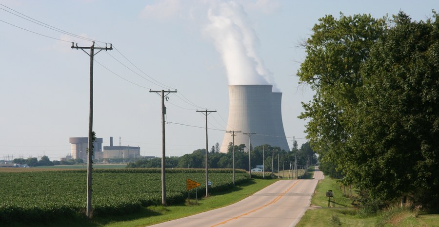Steam rises from a cooling tower at the Byron Generating Station, now run by Constellation, beside the reactor buildings and a country road south of Byron, Illinois, in July 2007.